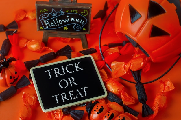 Fond d&#39;Halloween - Trick or Treat sur une étiquette en bois avec des bonbons noirs et orange