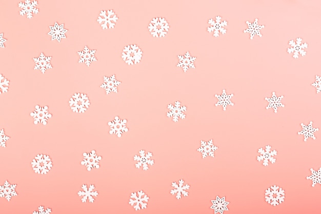 Fond d'hiver doucement rose avec des flocons de neige blancs. Disposition créative de Noël. Style scandinave minimaliste. Espace vide pour le texte, vue de dessus, mise à plat