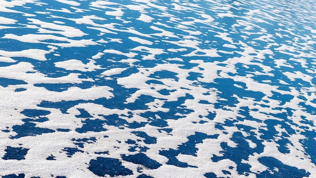 Fond d'hiver avec de la glace bleue de la rivière recouverte de neige blanche