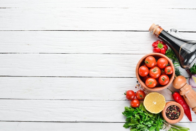 Fond de légumes Tomates fraîches paprika oignons et persil sur la table Vue de dessus Sur un fond en bois blanc Espace libre pour le texte