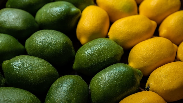 Fond de lime et de citrons sur le comptoir du marché. Citron biologique frais sur un supermarché alimentaire fermier local. Vue rapprochée des fruits dans la boîte en carton sur l'étagère de l'épicerie.