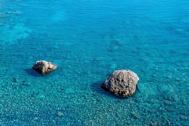 Fond marin, littoral côtier bleu transparent sur le récif de corail et deux rochers s'élèvent au-dessus de l'eau, vue de dessus