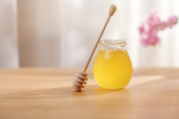 Fond de miel Miel doux dans un bocal en verre et une cuillère à miel sur une table en bois