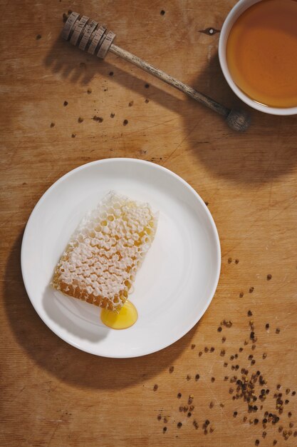 Fond de miel. Miel doux dans le peigne. Du miel frais dans un bocal en verre, des nids d'abeilles, une cuillère à miel et une abeille sur fond clair. Regarder.