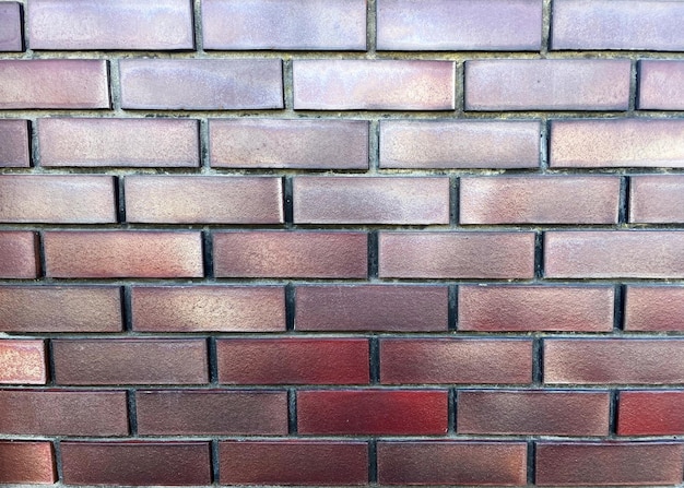 Fond de mur de briques avec des nuances de rouge et de violet. Texture de mur de brique