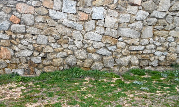 fond de mur en pierre et le sol de l&#39;herbe