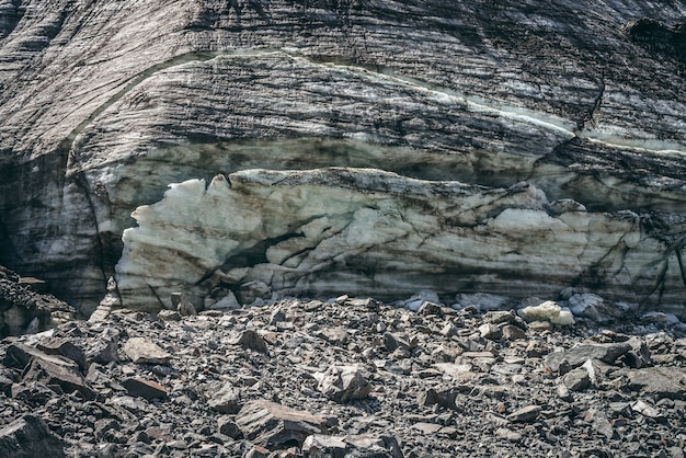 Fond de nature avec cascade de glace près du glacier avec fissures et rayures. Toile de fond naturelle avec mur de glace et moraines. Beau paysage avec mur glaciaire brillant et pierres au soleil. Texture glaciaire.