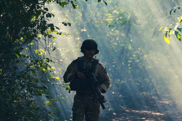 Sur fond naturel, un soldat de l'armée en uniforme de combat avec un fusil d'assaut ou une arme à feu.