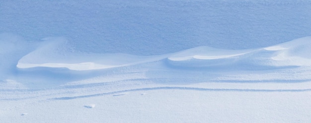 Fond neigeux surface enneigée de la terre après un blizzard le matin au soleil avec des couches de neige distinctes