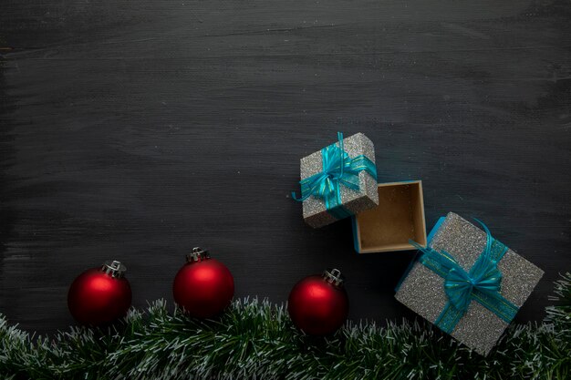 Fond de noël en bois noir avec des sphères rouges et des cadeaux avec un arc bleu