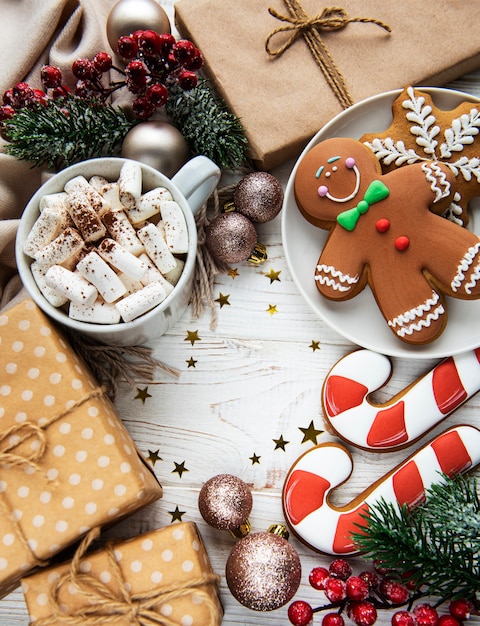 Fond de Noël avec boîte-cadeau, biscuits au cacao et au pain d'épice. Fond en bois blanc.