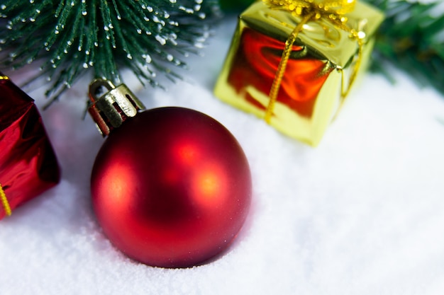 Photo fond de noël avec une boule rouge et, cadeau d'or dans la neige