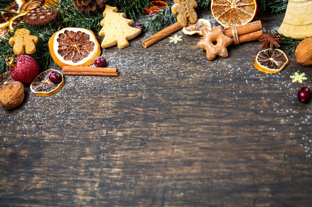 Fond de Noël avec une branche d'arbre de Noël, décoration festive, fruits secs, biscuits faits maison et épices saisonnières traditionnelles, vue de dessus