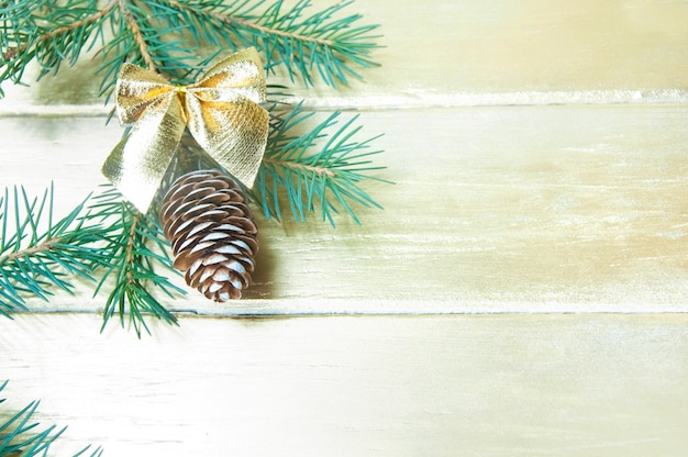 Fond de Noël, branche de sapin et pomme de pin avec un arc en or jaune sur une table en bois