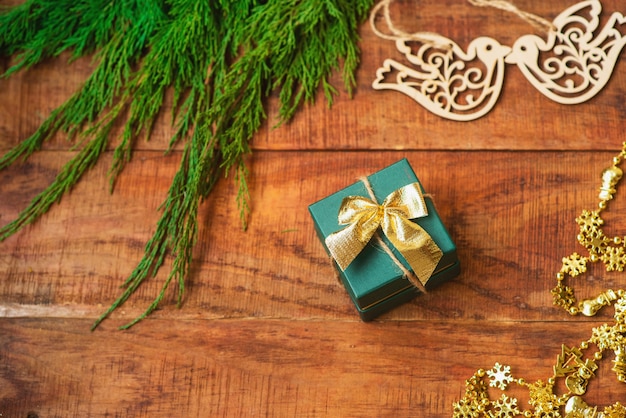 Fond de Noël. Branches d'épinette, cadeau, figures d'oiseaux en bois et guirlande dorée sur fond en bois. Espace de copie