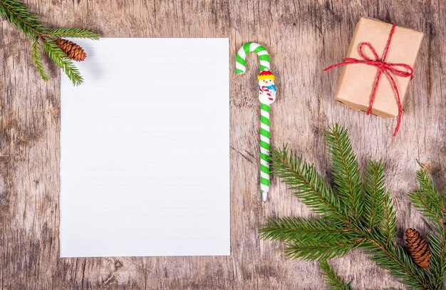 Fond de Noël avec des branches de sapin, boîte-cadeau et une feuille vierge