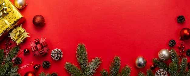 Fond de Noël avec des branches de sapin, cadeau ou cadeau et boule rouge sur fond de bannière rouge. Vue de dessus avec espace de copie