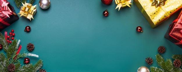 Fond de Noël avec des branches de sapin, cadeau ou cadeau, boule rouge et or sur fond de bannière vert foncé. Vue de dessus avec espace de copie.