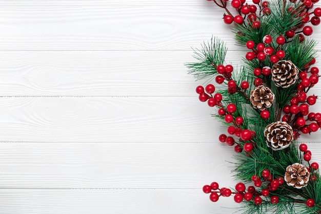 Fond De Noël Avec Des Branches De Sapin, Des Cônes Et Des Baies De Houx Rouges. Carte De Voeux De Nouvel An. Modèle Avec Espace De Copie. Mise à Plat. Place Pour Le Texte. Maquette Festive. Planches De Bois Blanc. L'hiver.