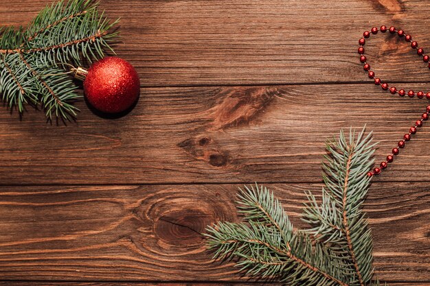 Fond de Noël avec brin de sapin et jouets rouges sur des planches en bois.