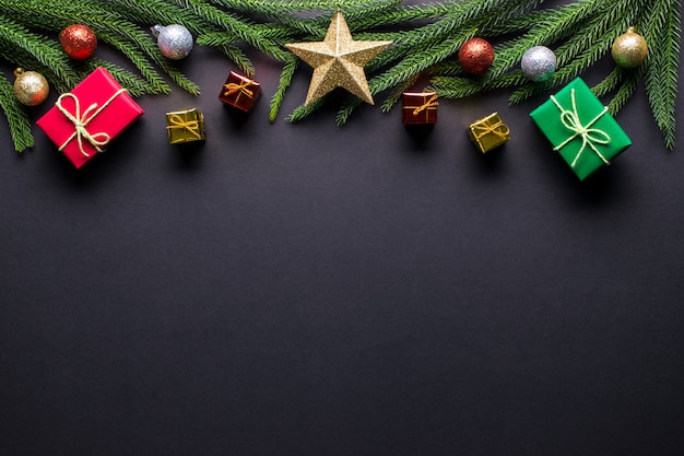 Fond de Noël Cadeaux, branches de sapin, décorations de boule sur fond noir. Lay plat, vue de dessus, espace de copie.