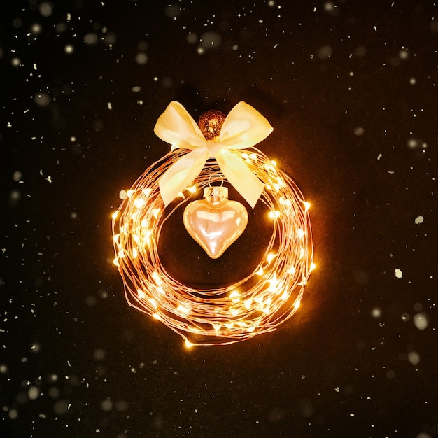Fond de Noël. Cercle lumineux d'une guirlande en forme de jouet de Noël sur fond noir avec des paillettes. Concept de design festif.