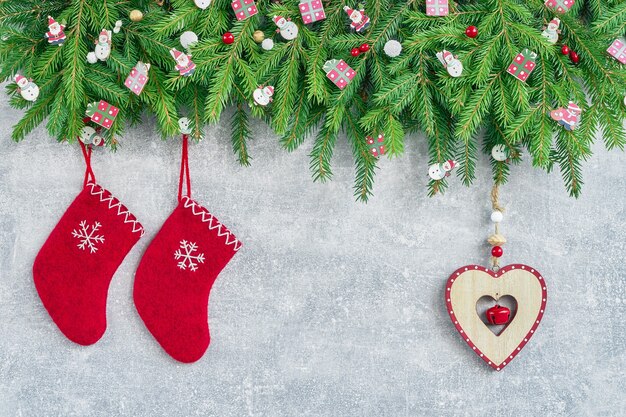 Fond de Noël. Chaussettes de Noël rouges et coeur avec des branches d'arbres de Noël sur fond gris. Espace de copie, vue de dessus.