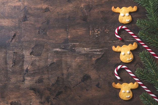 Fond de Noël. Composition de Noël avec des branches de sapin, cadeaux, bonbons, biscuits, cannelle sur fond de bois sombre