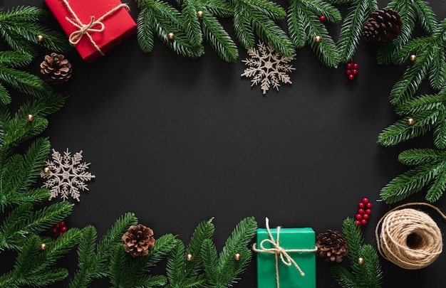 Fond de Noël avec décoration, cadeaux rouges et verts, flocon de neige, baies, branches de pin et cônes