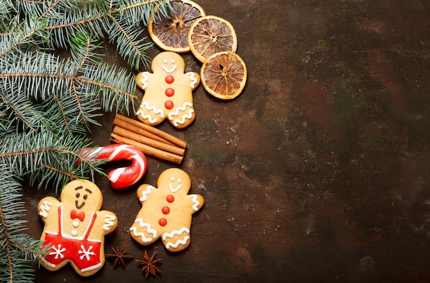 Fond de Noël avec des décorations : biscuits de pain d'épice et branches de sapin frais sur fond sombre, vue de dessus