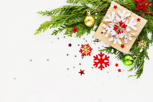 Fond de Noël et du nouvel an avec branche de thuya, décorations et cadeaux enveloppés dans du papier kraft avec des flocons de neige.