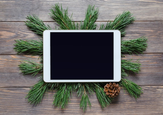 Fond de Noël ou du nouvel an sur un fond en bois. Tablette avec un écran vide pour les salutations. Mise à plat, vue de dessus, espace de copie.