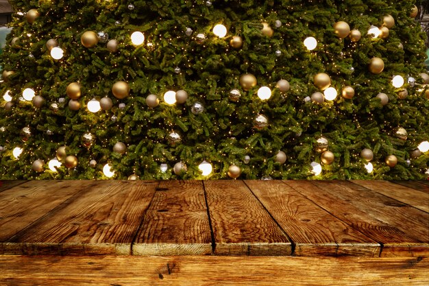 Fond de Noël et du nouvel an avec une table de terrasse en bois vide sur un arbre de Noël flou