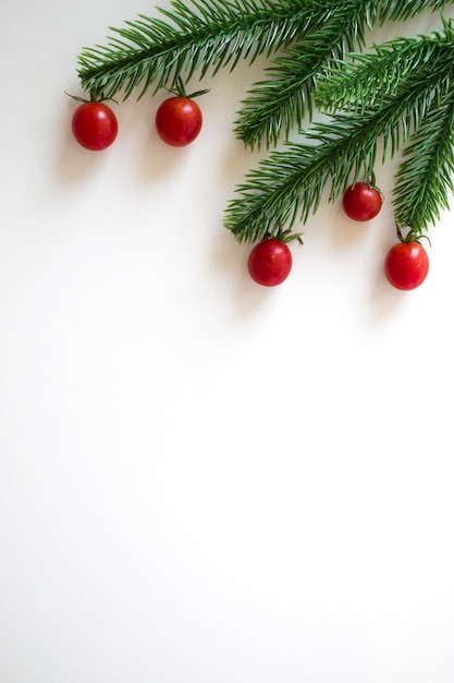 Fond de Noël avec espace copie, branches de sapin et tomates cerises rouges