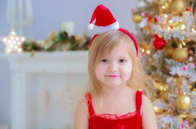 Fond de Noël une fille avec un chapeau de Père Noël se tient dans les décorations de Noël