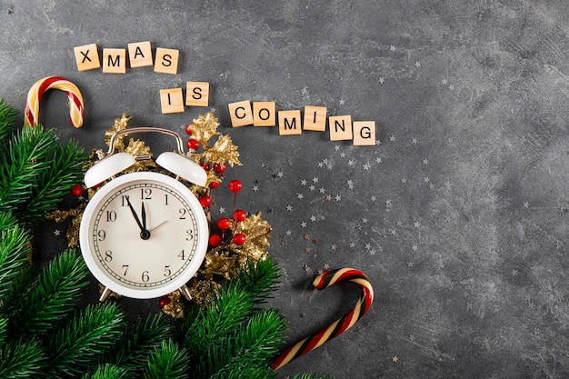 Fond de Noël avec l'inscription Noël arrive branches de sapin d'horloge et Noël