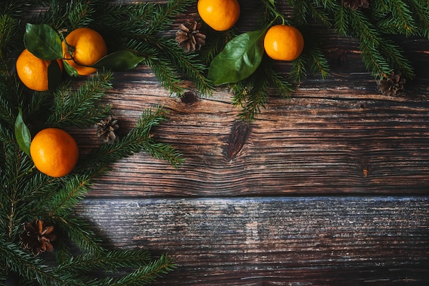 Fond de Noël avec des mandarines, des branches de sapin et des cônes