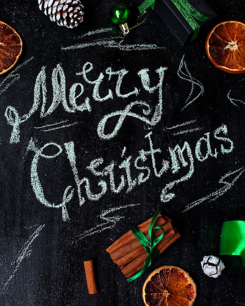 Fond de Noël avec les mots joyeux Noël, orange sec, pomme de pin blanche, boules vertes d'arbre de Noël