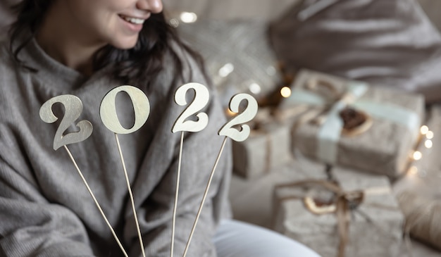 Fond de Noël avec des numéros en bois 2022 sur des bâtons dans des mains féminines