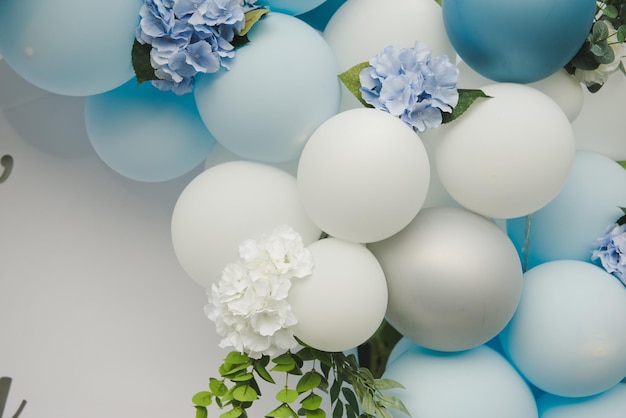 Fond de nombreux ballons blancs et bleus. Ballons bleus et blancs avec des fleurs pour la fête d'anniversaire