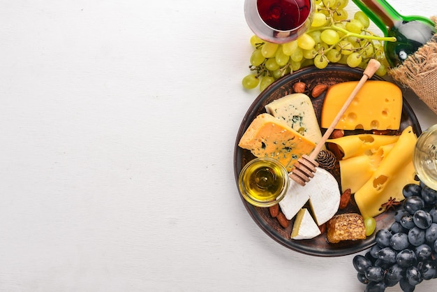 Fond de nourriture avec du fromage Blocs de fromage moisi Raisins Miel Noix sur fond blanc Copier l'espace Vue de dessus