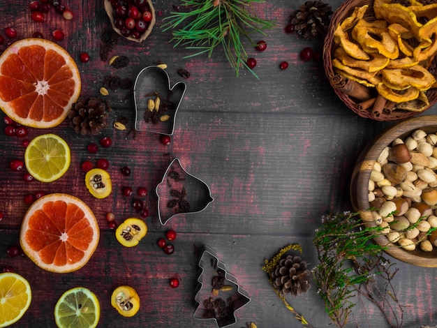 Photo fond de nourriture avec des épices de noël pommes séchées noix agrumes canneberges cydonia raisins secs et plat de cuisson sur fond en bois vue de dessus avec espace de copie