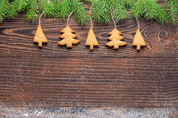 Photo fond de nouvel an avec des biscuits en forme d'arbre faits maison suspendus à des branches d'épinette