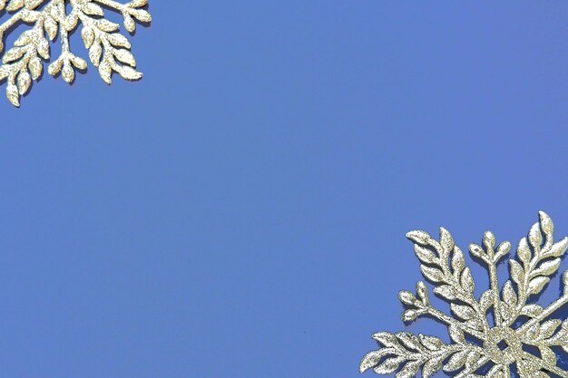 Fond de Nouvel An ou de Noël avec deux flocons de neige décoratifs sur les bords d'une feuille de papier de couleur Espace de copie Flocons de neige argentés blancs sur fond bleu