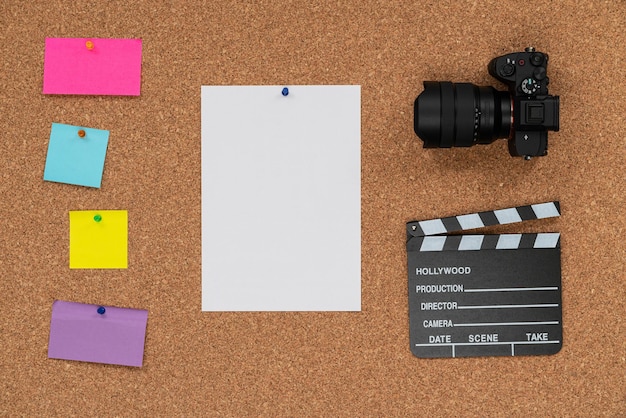 Fond de panneau de liège avec un bardeau et une caméra de cinéma et des notes adhésives de couleur prêtes à écrire