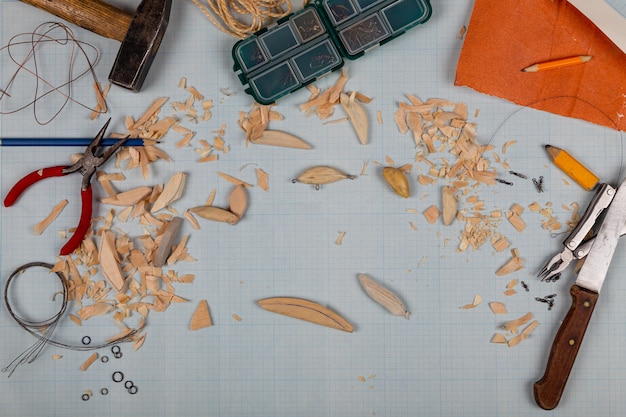 Photo fond de papier millimétré de tacles de pêche en bois faits à la main avec des outils et des blancs.