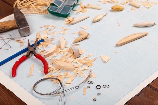 Photo fond de papier millimétré de tacles de pêche en bois faits à la main avec des outils et des blancs.