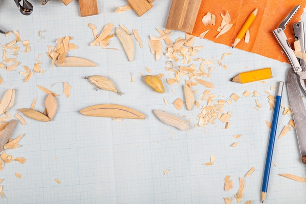 Photo fond de papier millimétré de tacles de pêche en bois faits à la main avec des outils et des blancs.