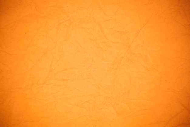 Fond de papier orange froissé.