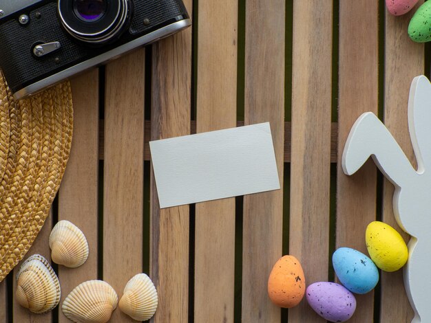 Fond de Pâques avec appareil photo chapeau de paille oeufs colorés et lapin blanc